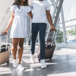A couple walking through their terminal at an airport in sneakers and easy-to-wear travel outfits.