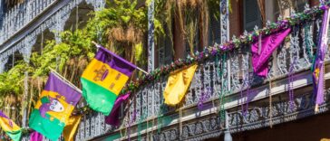 A building in the French Quarter of New Orleans decorated with colorful beads, flags, and banners to celebrate Mardi Gras.