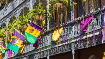 A building in the French Quarter of New Orleans decorated with colorful beads, flags, and banners to celebrate Mardi Gras.