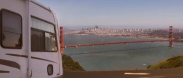 An RV parked at a viewpoint that is overlooking the Golden Gate Bridge in San Francisco on a sunny day.